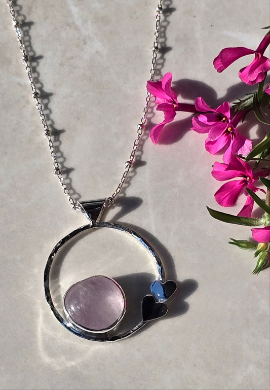 Sterling silver hammered ring pendant with bezel-set tumbled rose quartz and two heart details on 19 inch beaded chain