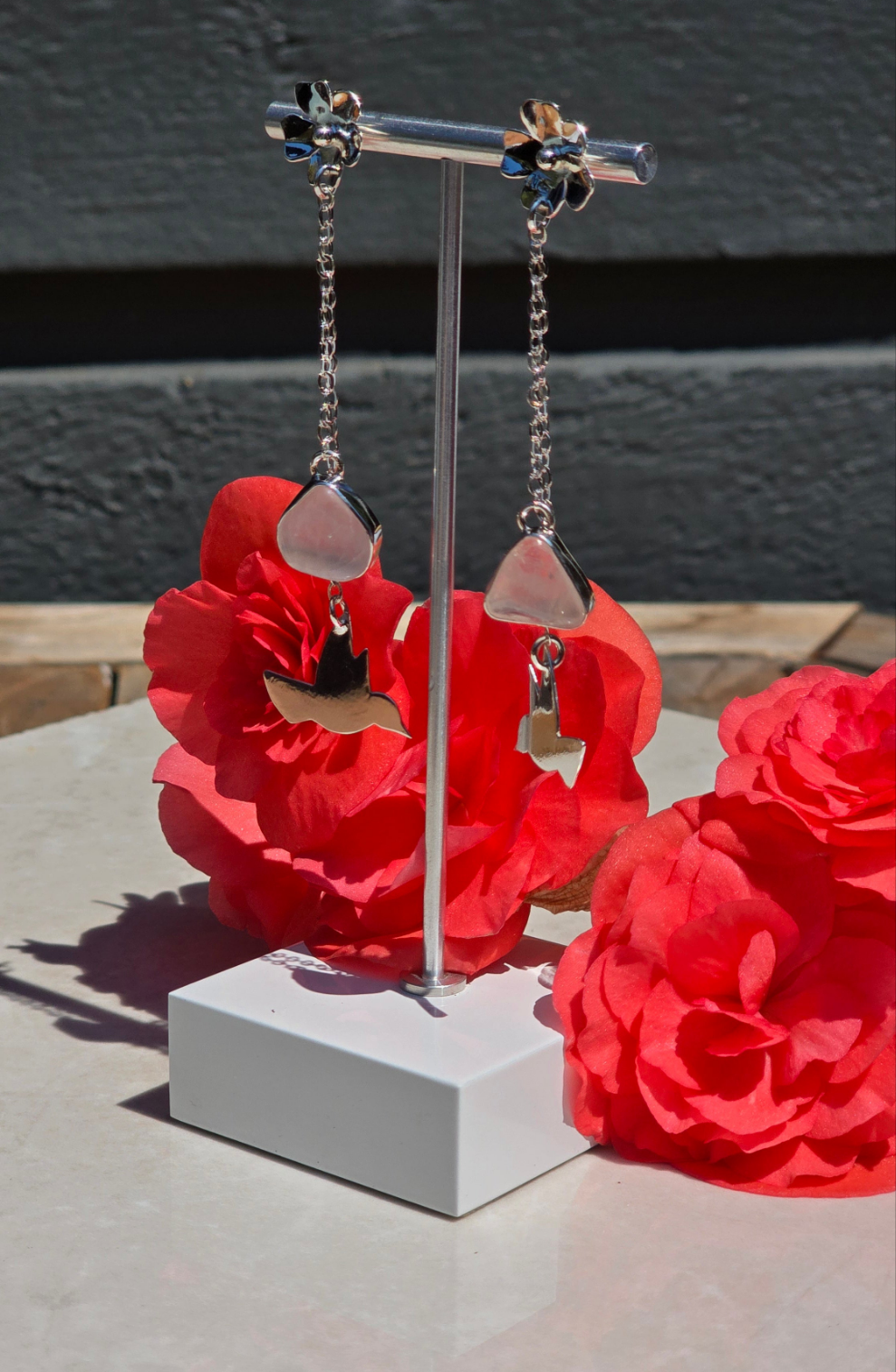 Sterling silver dangling earrings with flower stud, bezel-set open-back rose quartz, and cutout hummingbird charm