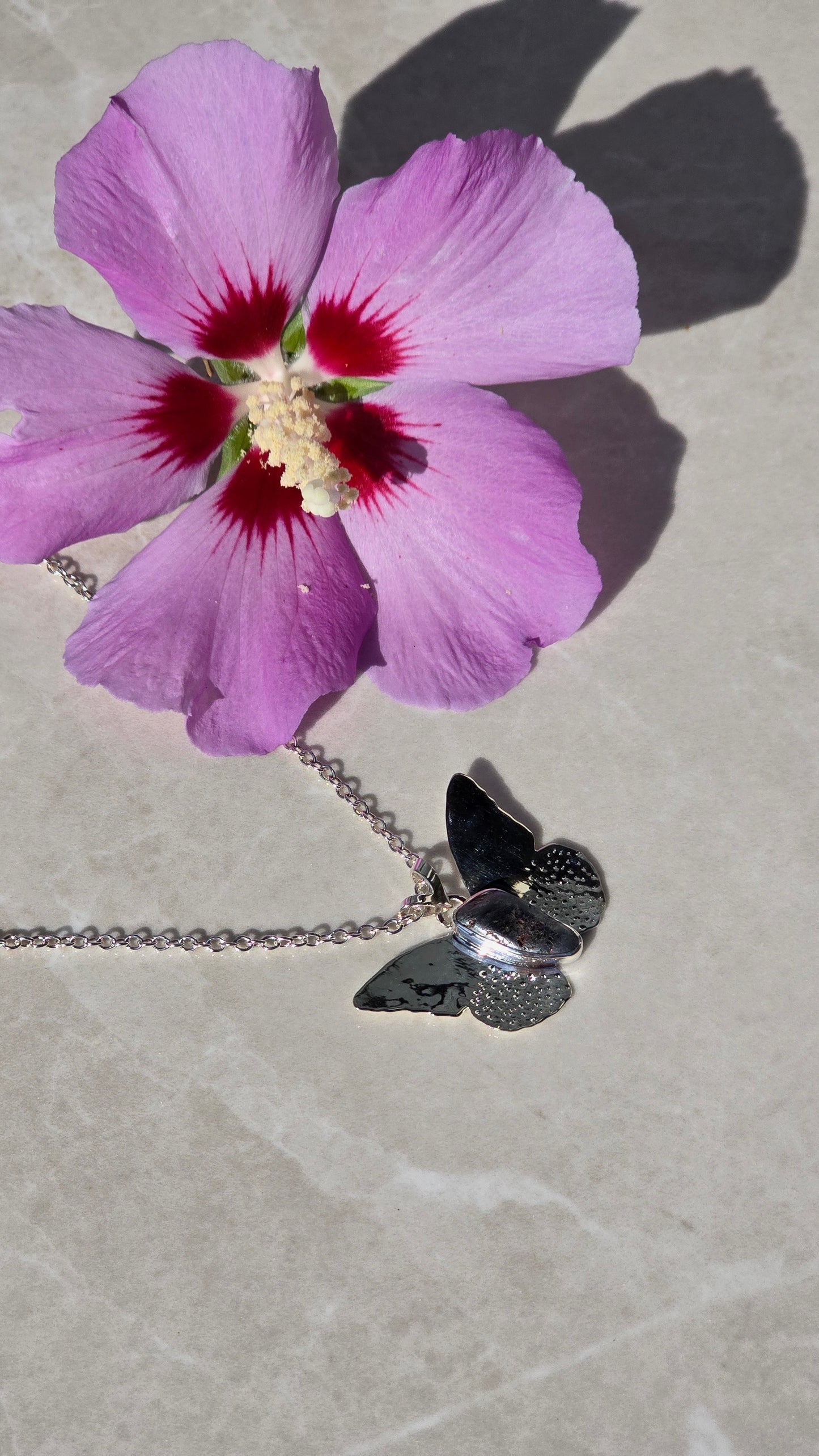 Sterling silver butterfly necklace with bezel-set magnetite body and textured wings on 19-inch chain