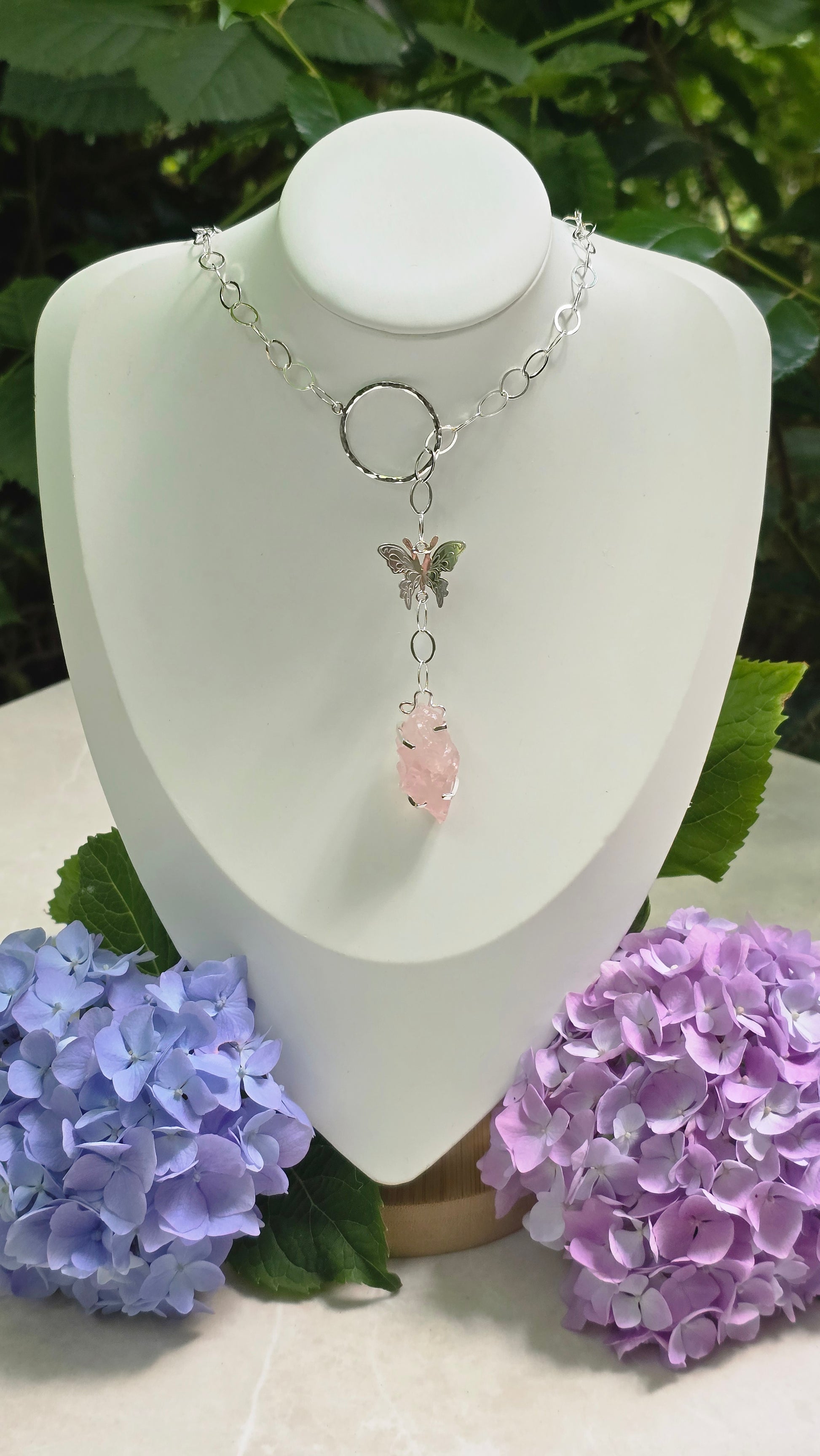 Handcrafted sterling silver Flutter & Bloom necklace featuring a hammered circle, butterfly, and genuine raw rose quartz crystal in a handcrafted prong setting by Vanessa Andrea Jewellery.
