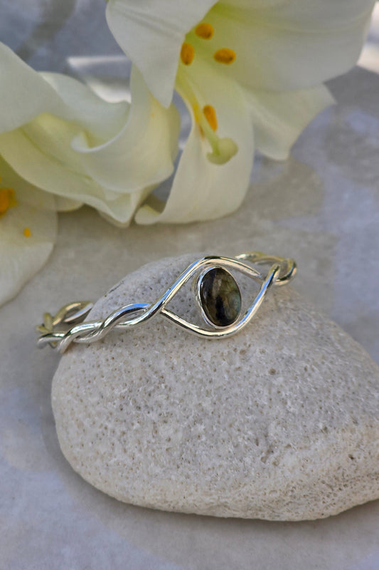 Sterling silver twisted cuff bracelet with oval labradorite cabochon in bezel setting, eye-shaped design, handmade gemstone jewelry